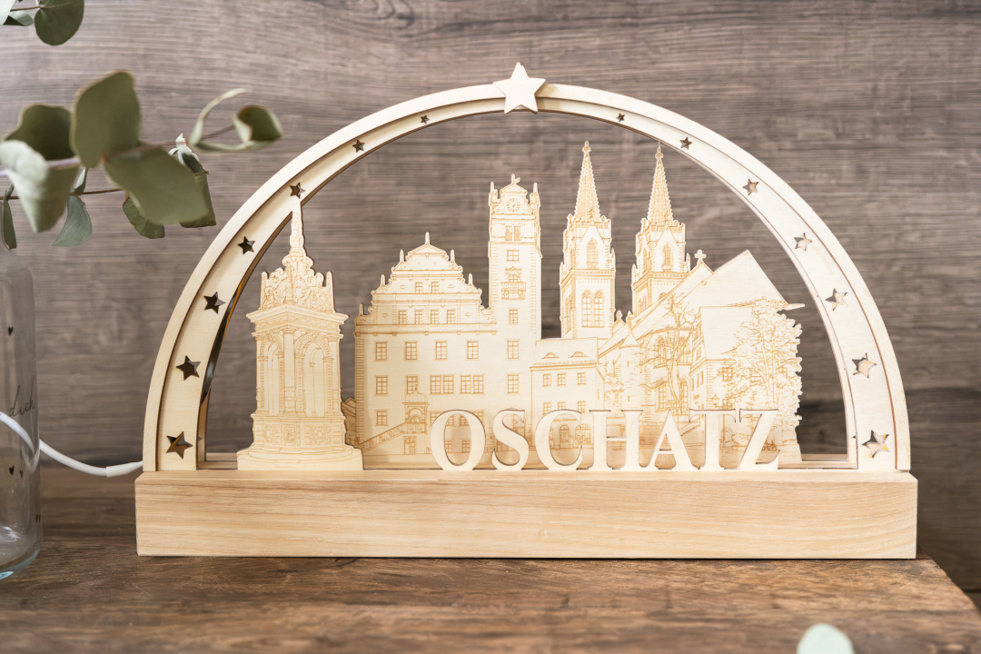 LED-Schwibbogen komplett aus Holz mit gravierter Stadtsilhouette von Oschatz (Brunnen, Rathaus, Kirchtürme) und dem Schriftzug „Oschatz", umrahmt von Sternen, warmweißes Licht